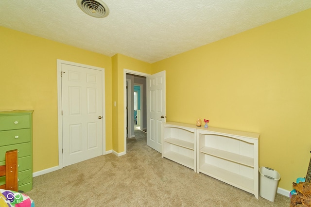 bedroom featuring light carpet, visible vents, and a textured ceiling