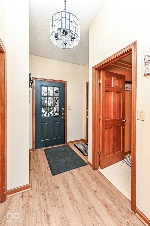 entryway featuring a textured ceiling, an inviting chandelier, and light hardwood / wood-style floors