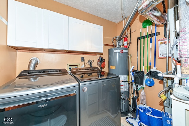 clothes washing area featuring washer and dryer, cabinets, water heater, and a textured ceiling