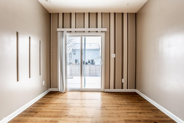 spare room with baseboards and light wood finished floors