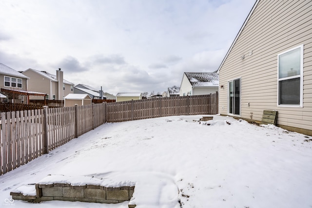 yard layered in snow featuring a fenced backyard and a residential view