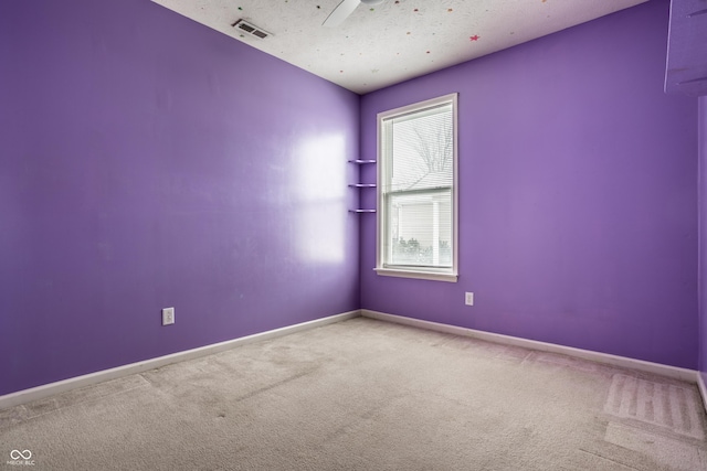 spare room featuring visible vents, carpet, a textured ceiling, ceiling fan, and baseboards