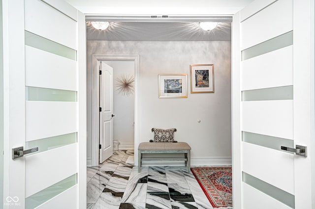 corridor with marble finish floor and baseboards