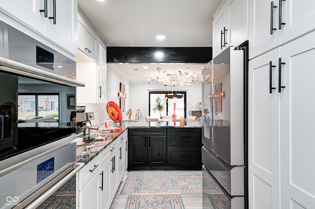 kitchen with a healthy amount of sunlight, light stone countertops, appliances with stainless steel finishes, and white cabinets