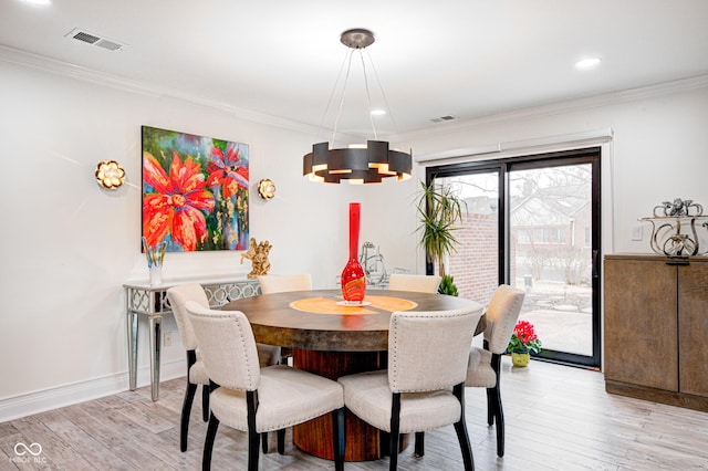 dining area featuring light wood-style flooring, visible vents, and crown molding