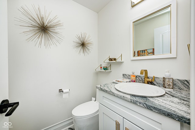 bathroom featuring toilet, baseboards, and vanity