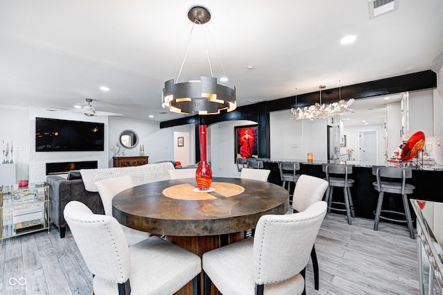 dining space featuring recessed lighting, a large fireplace, visible vents, and light wood finished floors