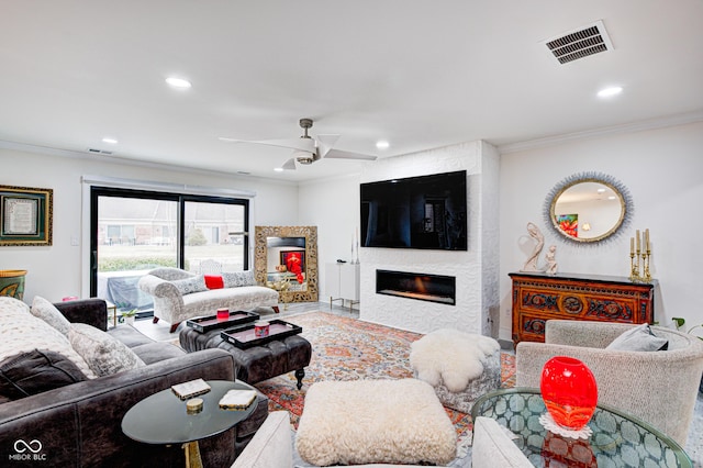 living area featuring crown molding, recessed lighting, visible vents, and a fireplace