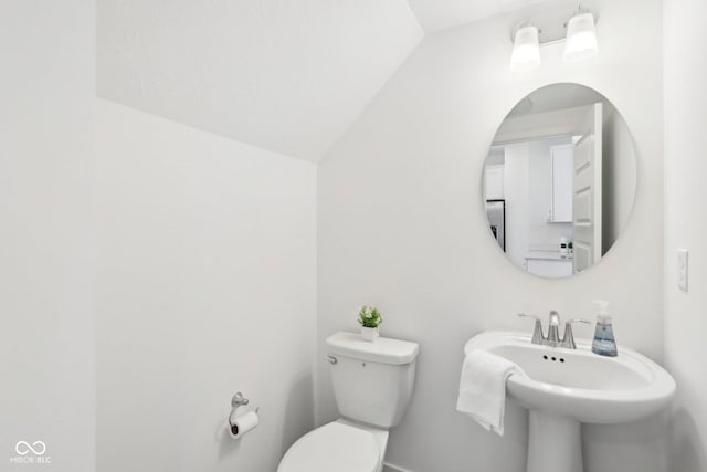 bathroom with sink, toilet, and vaulted ceiling