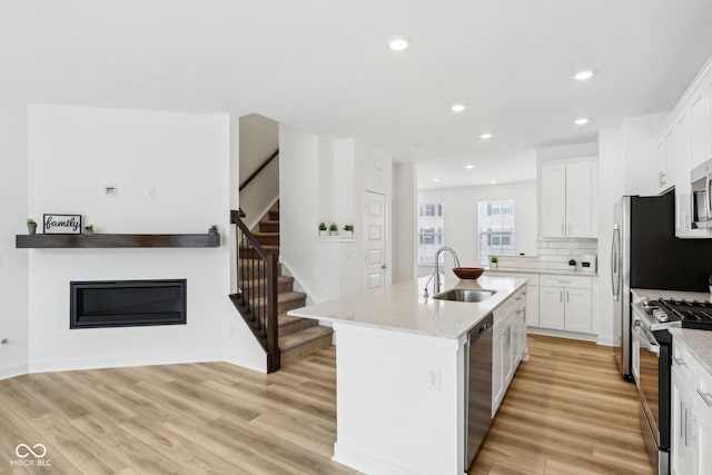 kitchen featuring appliances with stainless steel finishes, sink, an island with sink, and white cabinetry