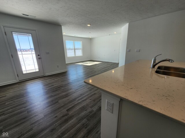 kitchen with dark wood-type flooring, visible vents, a textured ceiling, and a sink