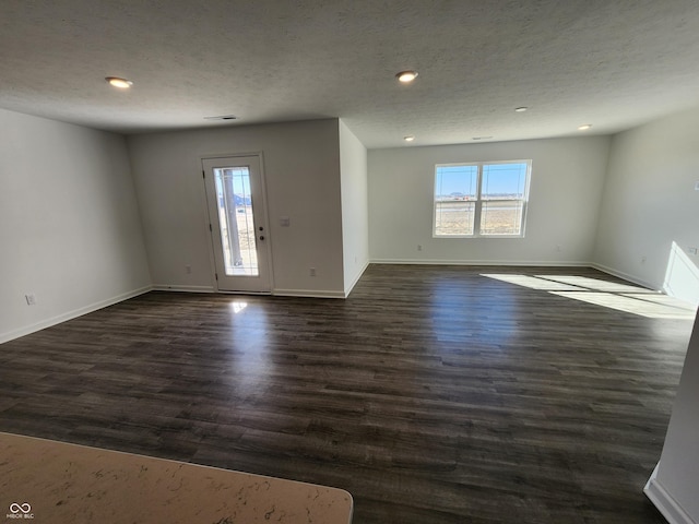 spare room with a healthy amount of sunlight, baseboards, and dark wood finished floors