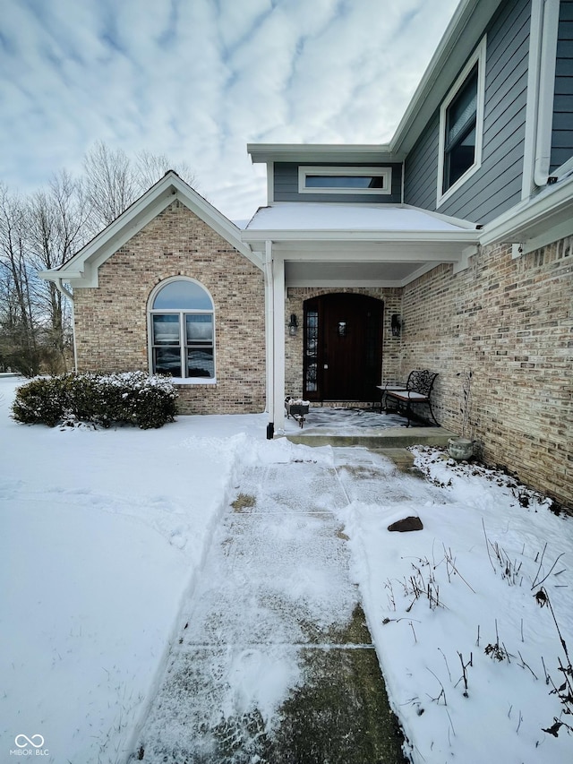 snow covered property entrance featuring a porch