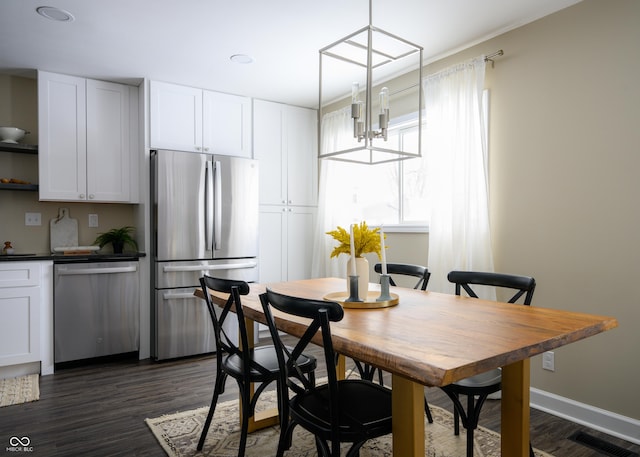 dining space with dark wood-style floors, baseboards, visible vents, and an inviting chandelier