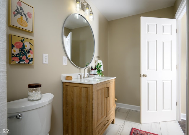 half bathroom with toilet, marble finish floor, baseboards, and vanity