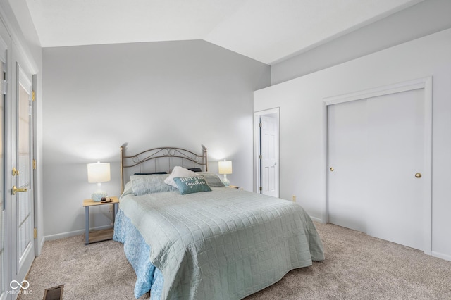 bedroom with vaulted ceiling, light colored carpet, and a closet