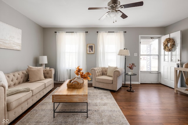 living room featuring dark wood-style flooring, a ceiling fan, and baseboards