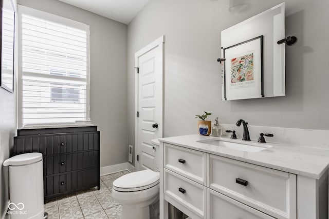 bathroom with tile patterned flooring, baseboards, vanity, and toilet