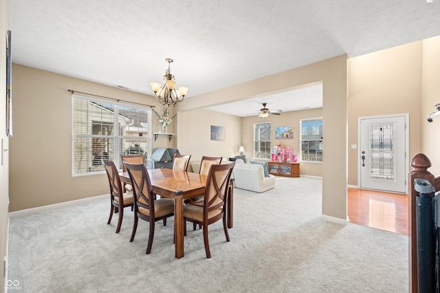 dining area with ceiling fan with notable chandelier, a textured ceiling, and light colored carpet