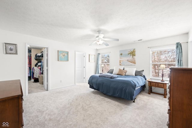 carpeted bedroom featuring multiple windows, a closet, a walk in closet, and a textured ceiling