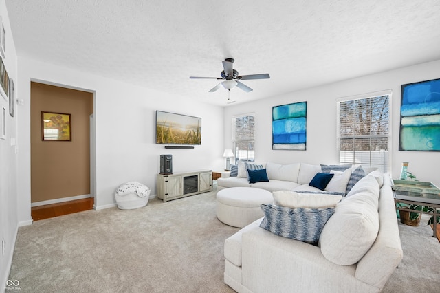 carpeted living room featuring ceiling fan and a textured ceiling