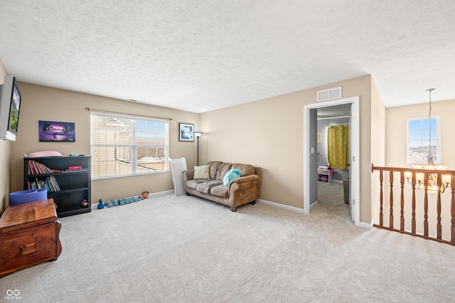 living room featuring a textured ceiling, carpet flooring, and a notable chandelier