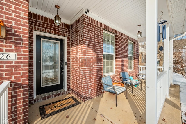 property entrance featuring brick siding and a porch