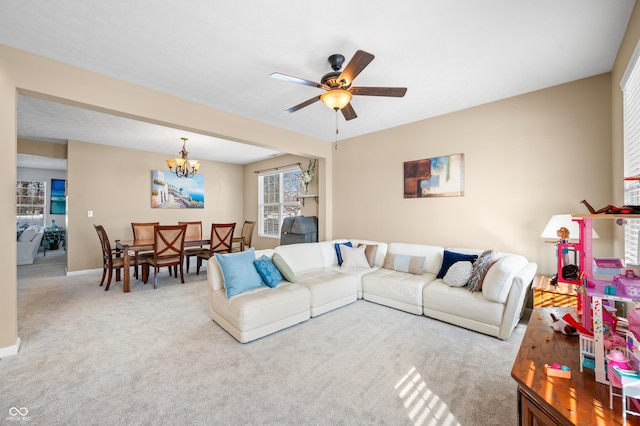 carpeted living room featuring ceiling fan with notable chandelier