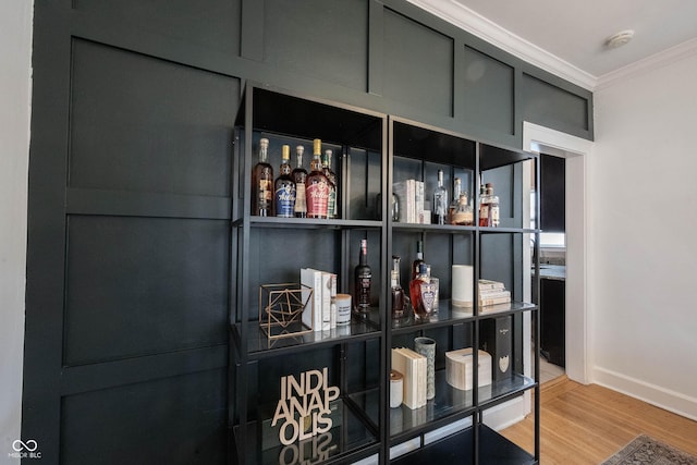 interior space featuring hardwood / wood-style floors, bar, and crown molding