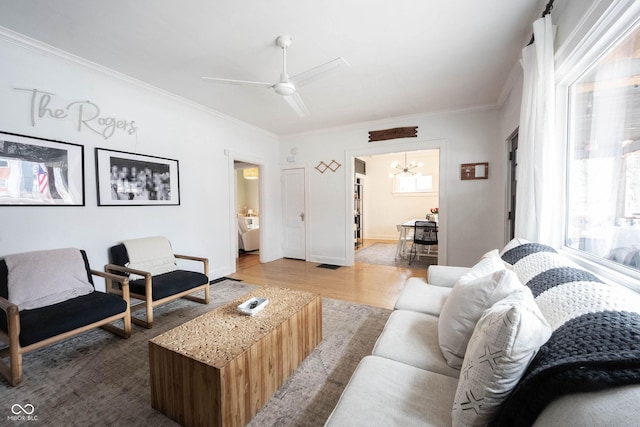 living room with wood-type flooring, crown molding, and ceiling fan with notable chandelier