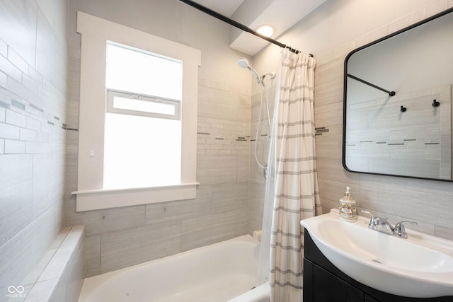 bathroom with shower / tub combo with curtain, tile walls, and vanity