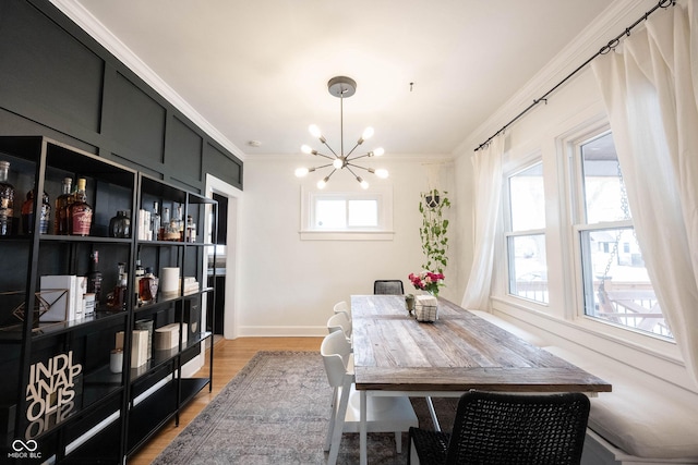 dining space with ornamental molding, light hardwood / wood-style floors, and a notable chandelier