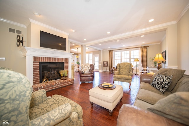 living area with visible vents, a brick fireplace, crown molding, and hardwood / wood-style flooring