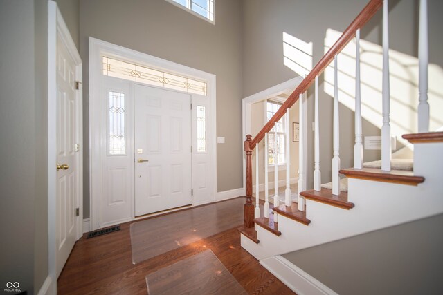 entryway featuring stairs, a high ceiling, wood finished floors, and visible vents