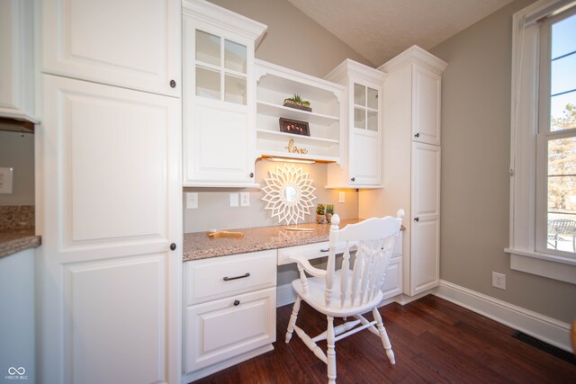 office space featuring baseboards, dark wood-type flooring, vaulted ceiling, and built in study area