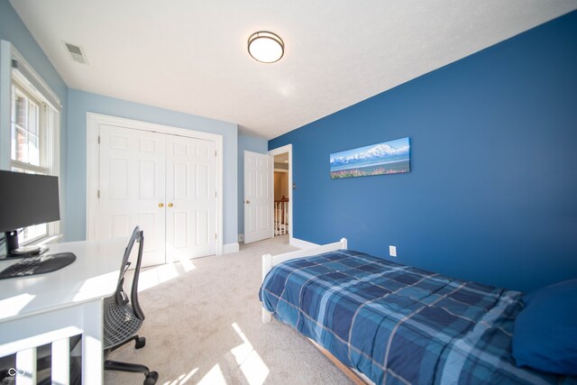 carpeted bedroom with a closet, visible vents, and baseboards