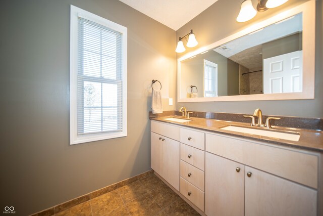 full bathroom with double vanity, baseboards, and a sink