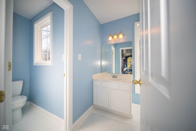 half bathroom featuring vanity, toilet, baseboards, and tile patterned flooring