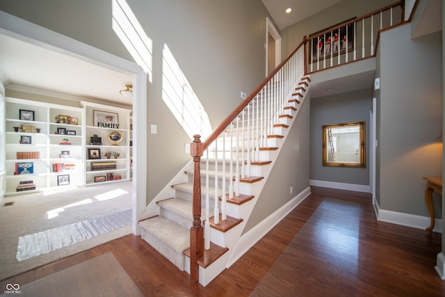 stairs featuring recessed lighting, a high ceiling, baseboards, and wood finished floors