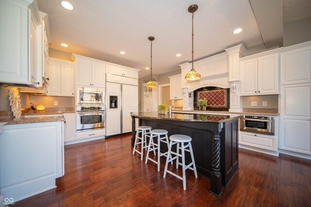 kitchen featuring a kitchen breakfast bar, built in appliances, dark wood-style floors, and white cabinetry