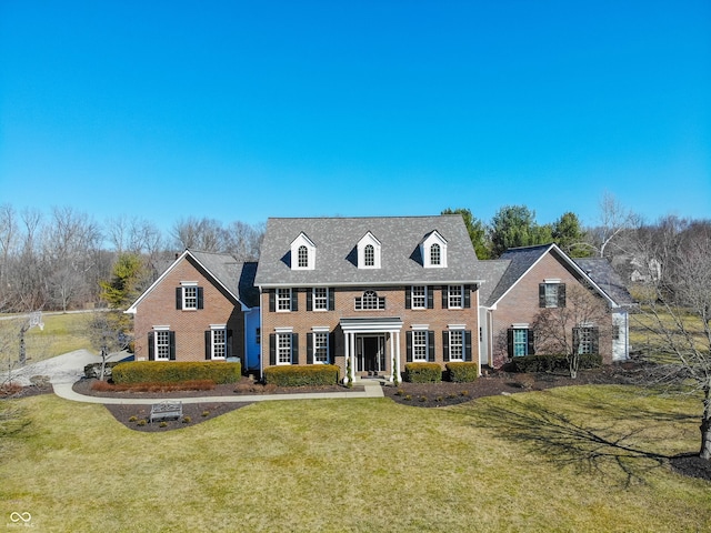 colonial inspired home featuring a front lawn and brick siding