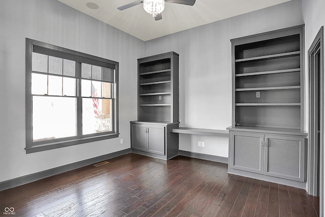 unfurnished office with dark wood-type flooring, built in desk, and ceiling fan