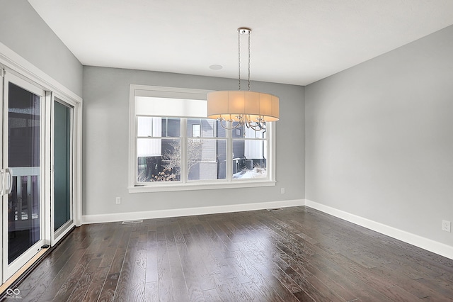 empty room featuring a chandelier, dark hardwood / wood-style floors, and a healthy amount of sunlight