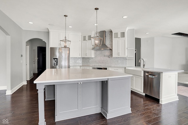 kitchen featuring appliances with stainless steel finishes, sink, a large island with sink, wall chimney exhaust hood, and white cabinets