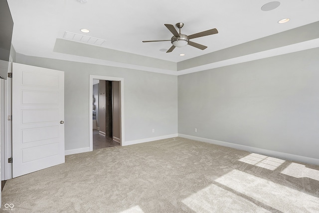 carpeted empty room with ceiling fan and a raised ceiling