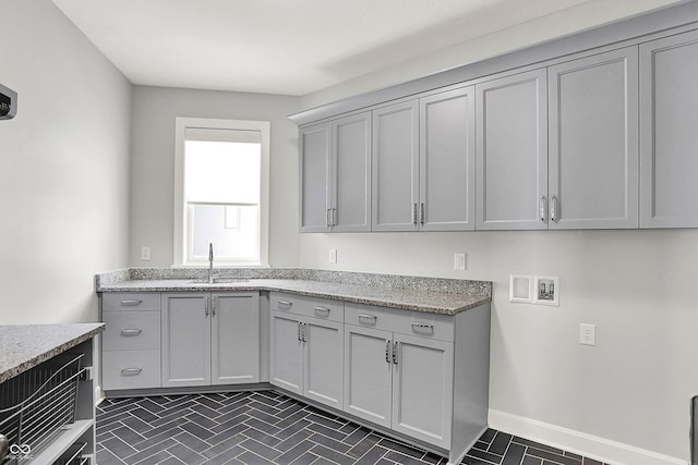 kitchen with sink, gray cabinetry, and light stone counters