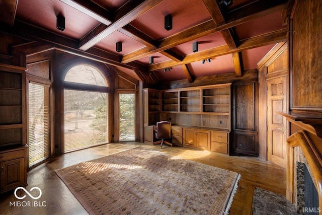 unfurnished office featuring beam ceiling, built in desk, wood walls, and coffered ceiling