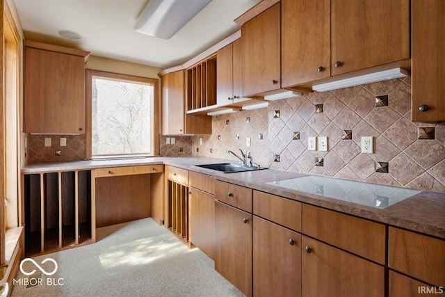 kitchen featuring black electric cooktop, sink, tasteful backsplash, and light stone countertops