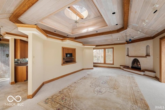 interior space with a skylight, light carpet, wooden ceiling, a tray ceiling, and ornamental molding