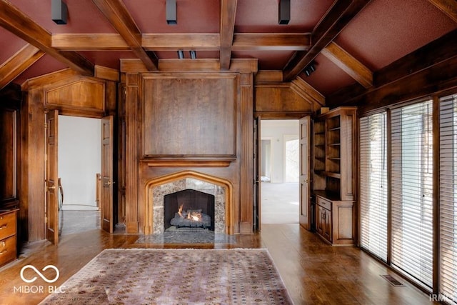 unfurnished living room featuring hardwood / wood-style flooring, a premium fireplace, vaulted ceiling with beams, and wood walls